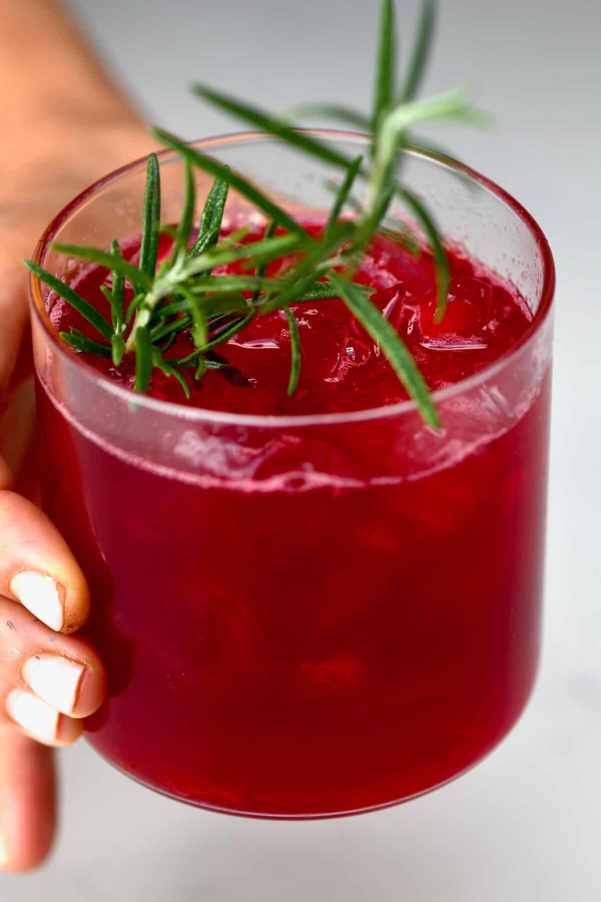 A hand holding a glass with cranberry juice