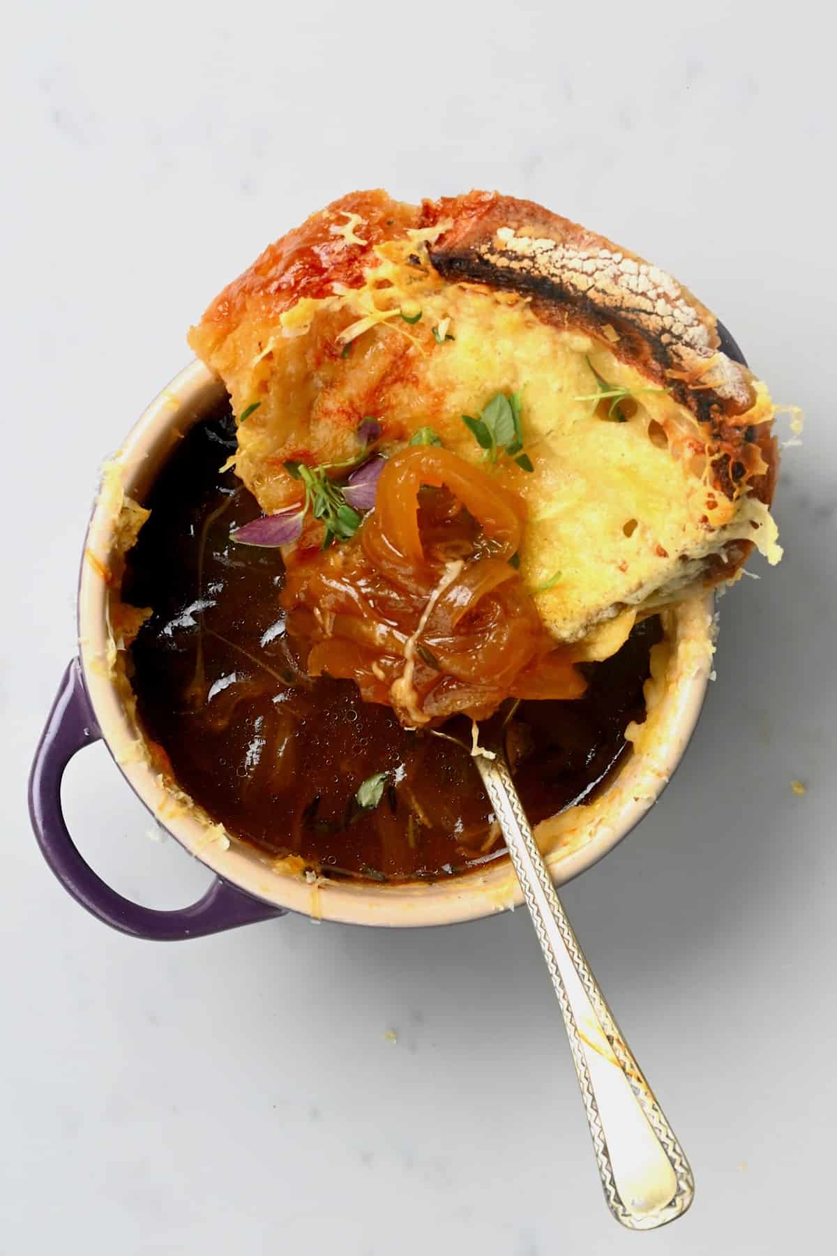 A spoon dipped in a bowl with onion soup