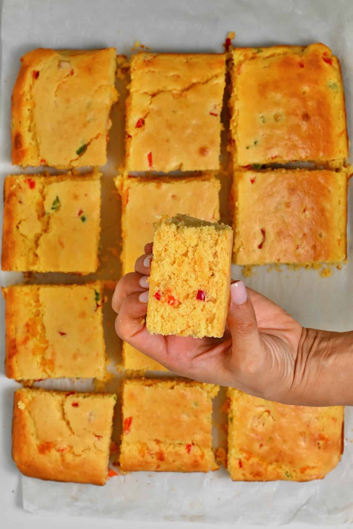 A hand holding a square of cornbread