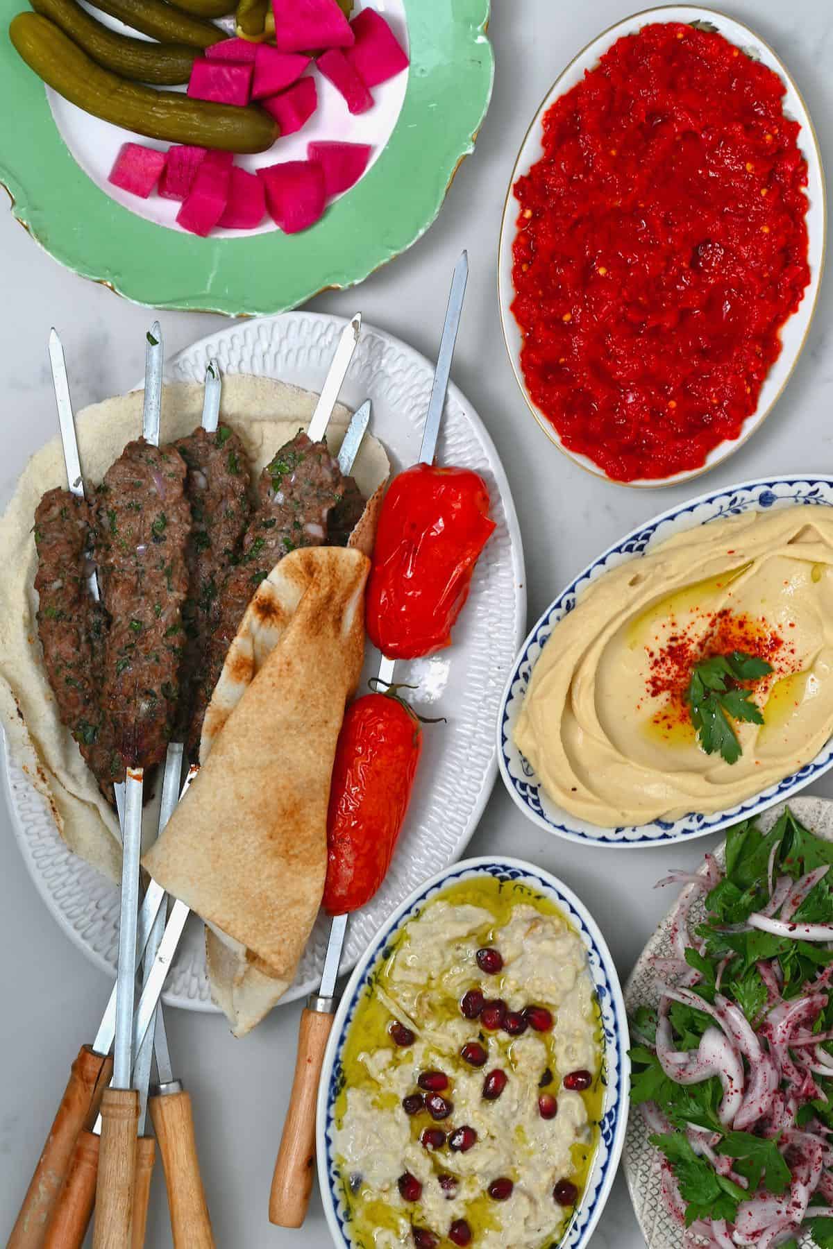 A selection of kofta skewers dips and pickles