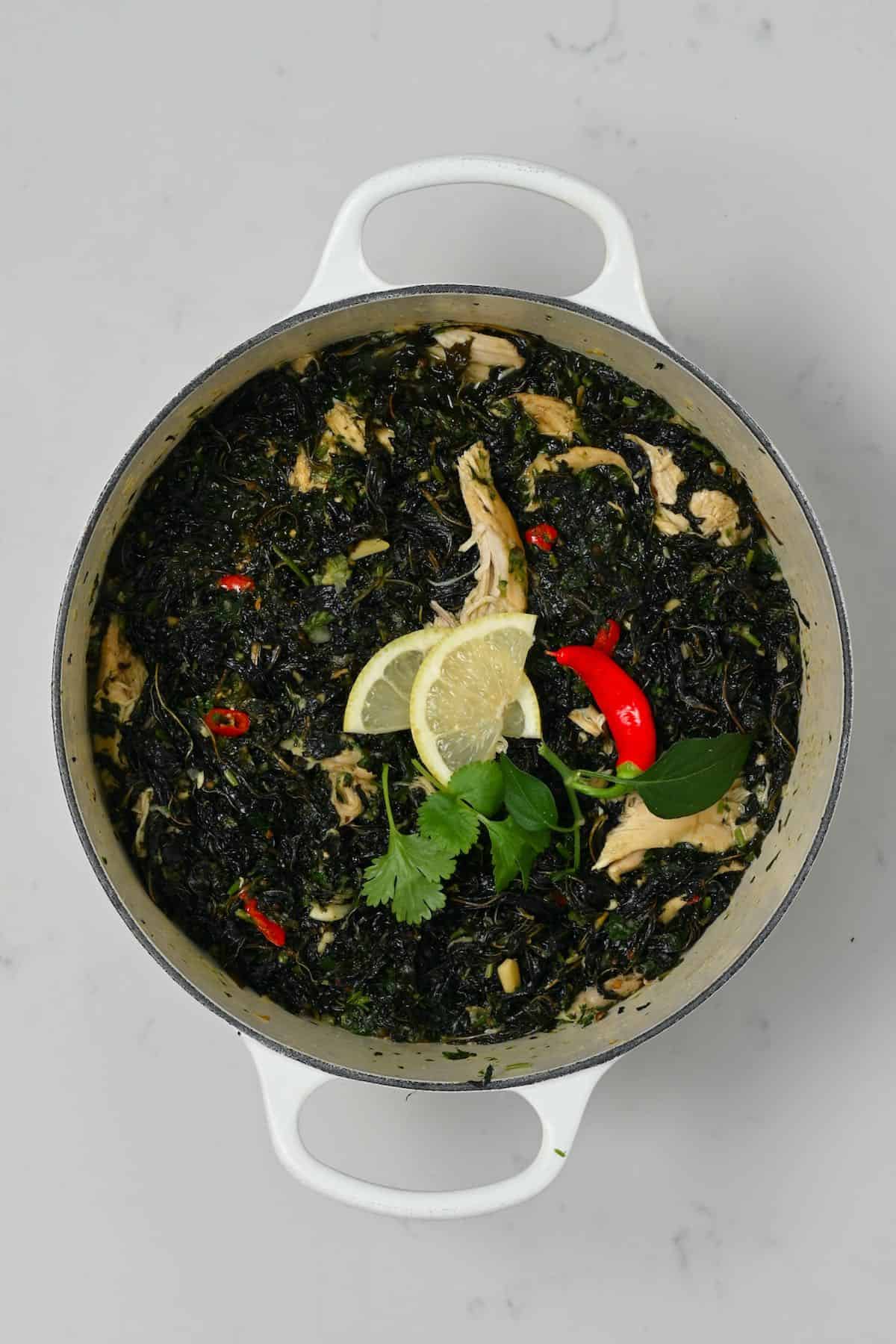 Molokhia with chicken in a saucepan with lemon and chili