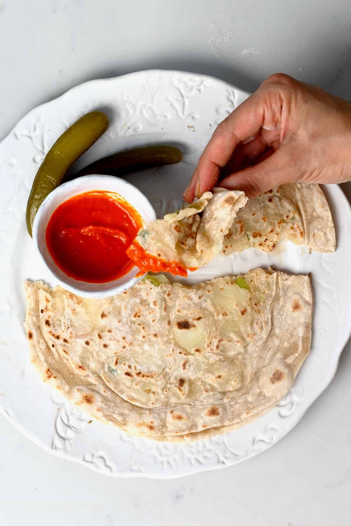 A serving of potato roti with chili sauce and pickles