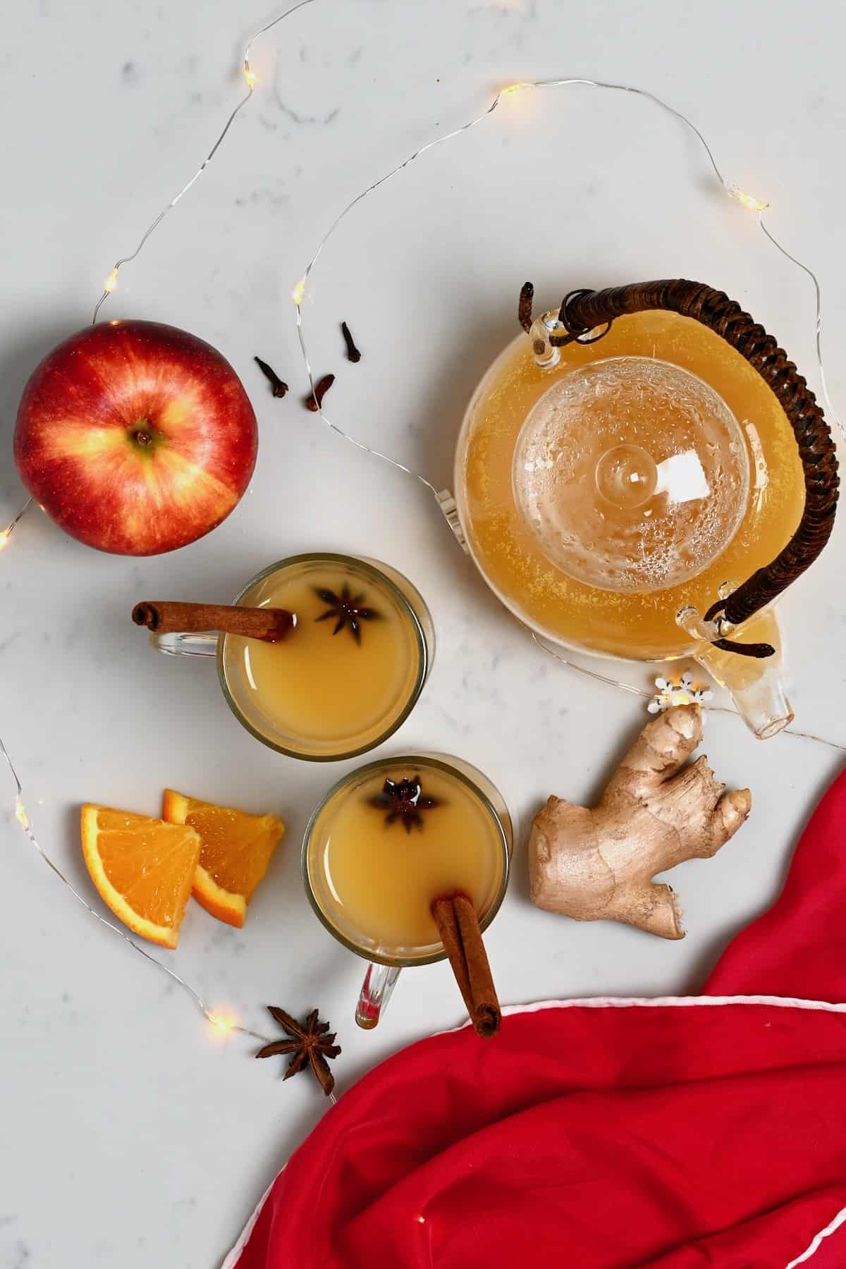 Two glasses and a teapot with spiced apple cider (wassail)