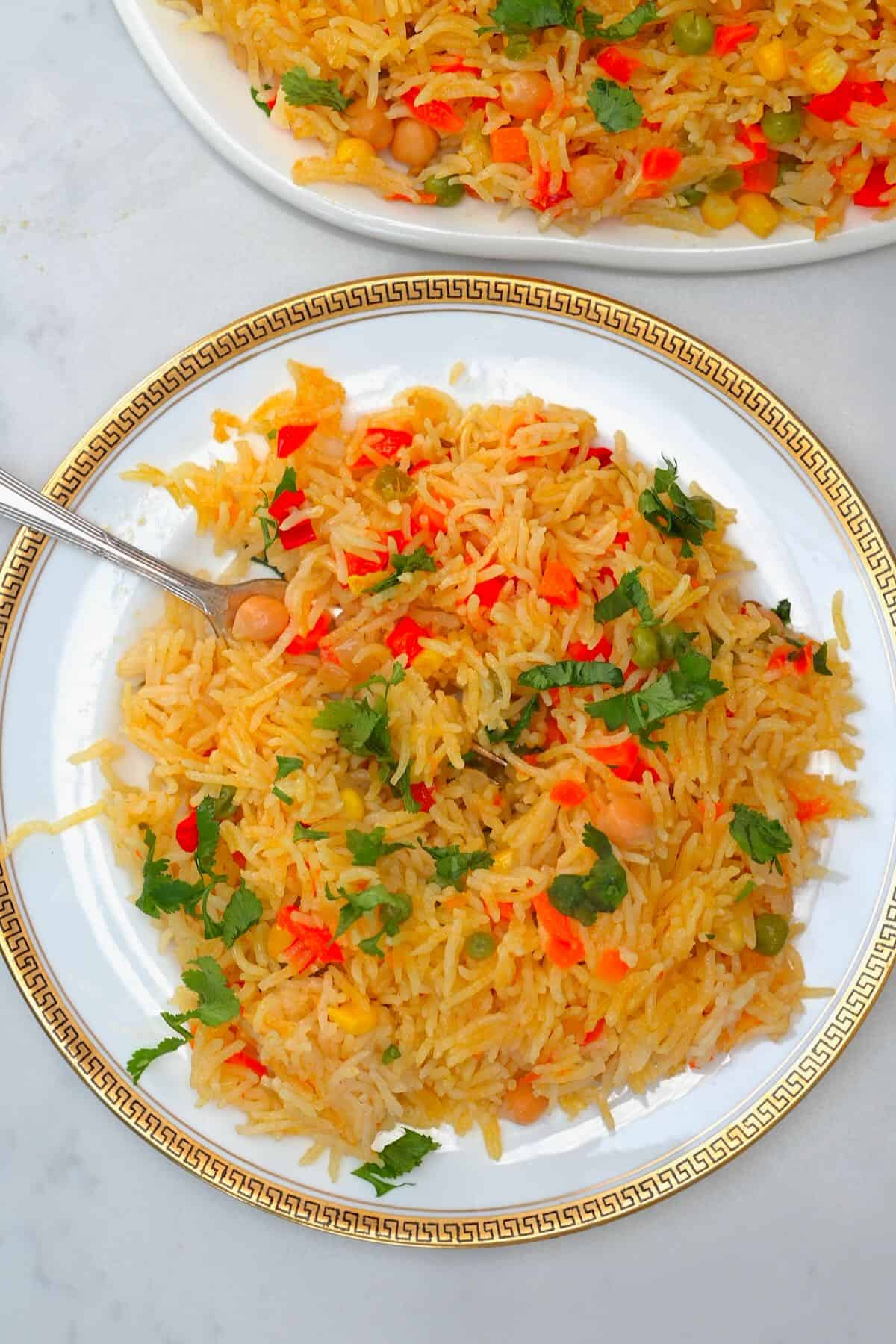 A serving of vegetable rice in a plate with a fork