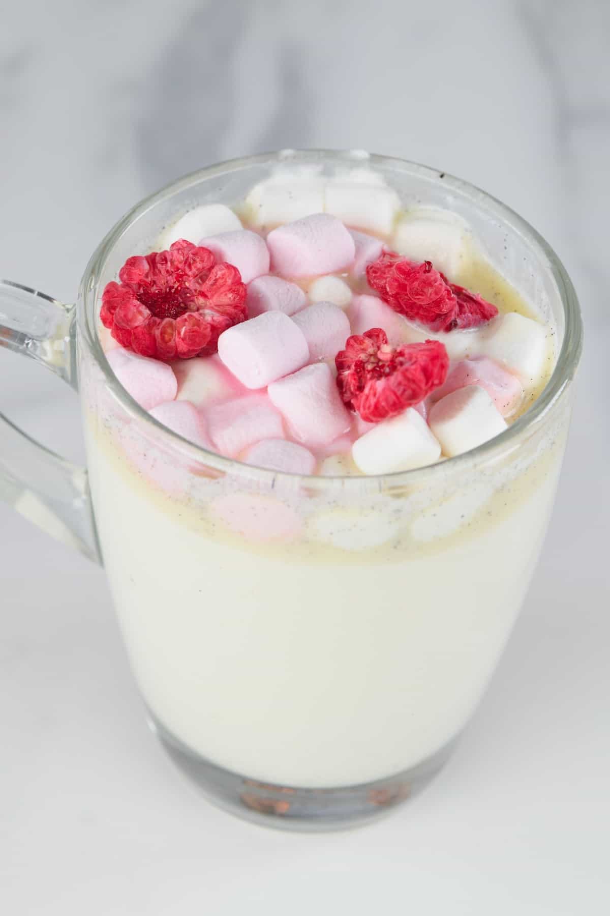 side view of white hot chocolate with marshmallows and dried raspberries