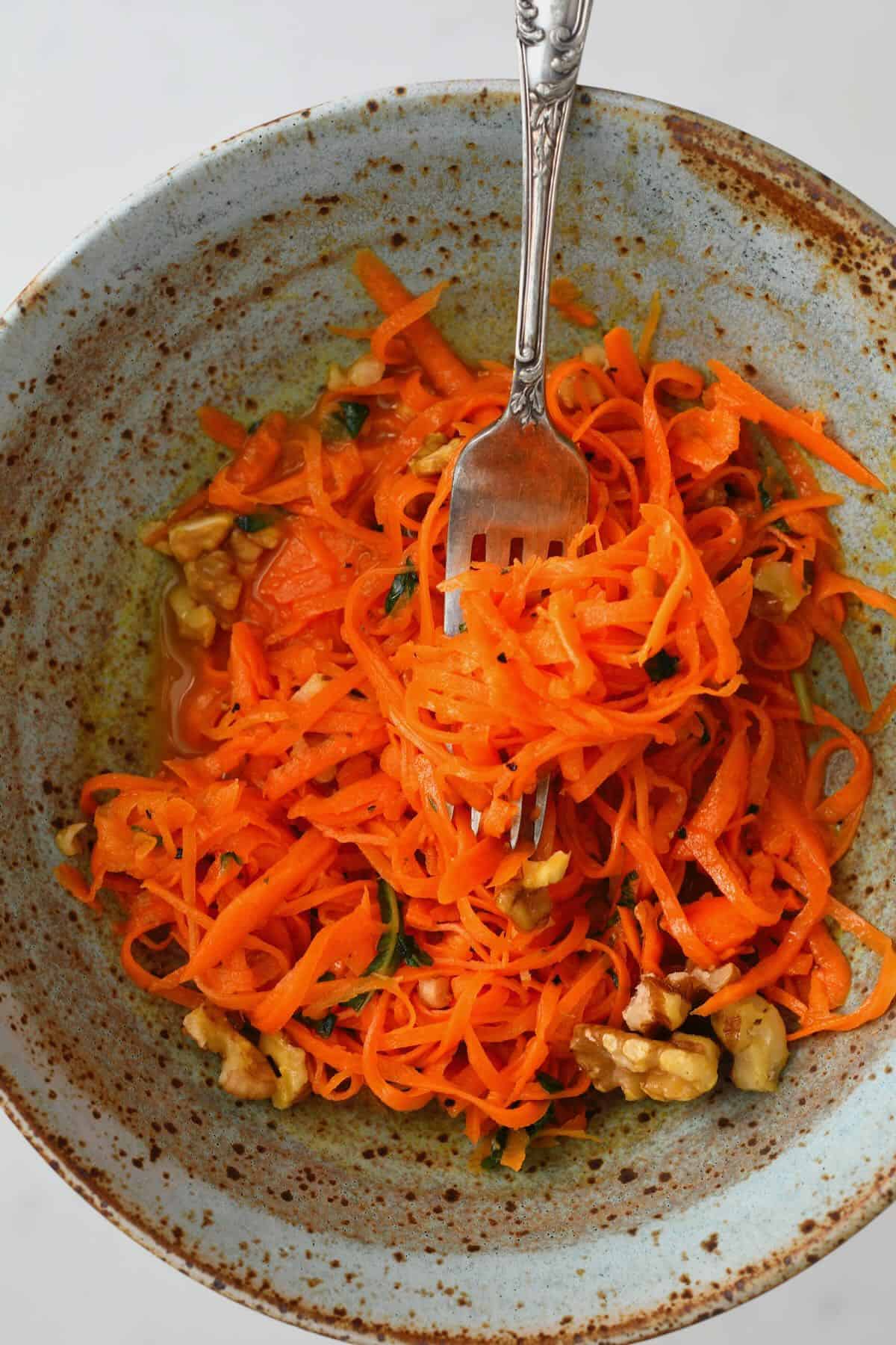 A serving of carrot salad topped with walnuts