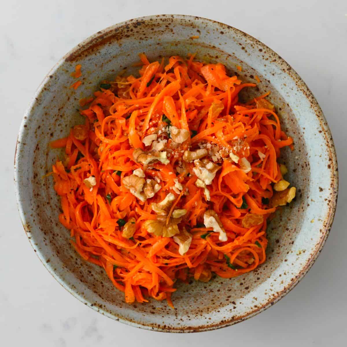 A serving of carrot salad topped with walnuts - 48