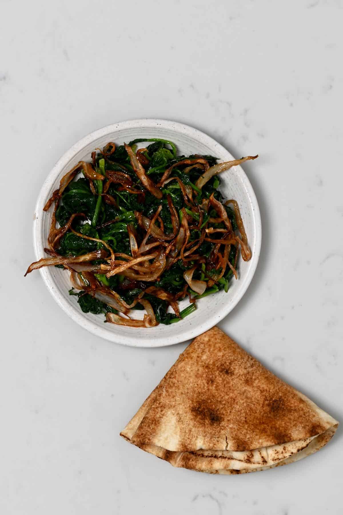 A small plate with spinach and crispy onion