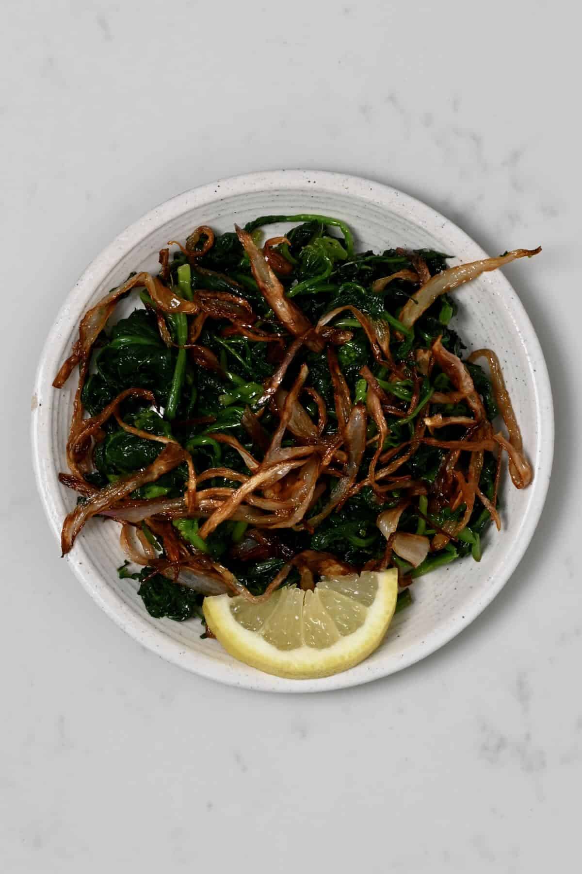 A small plate with spinach and crispy onion