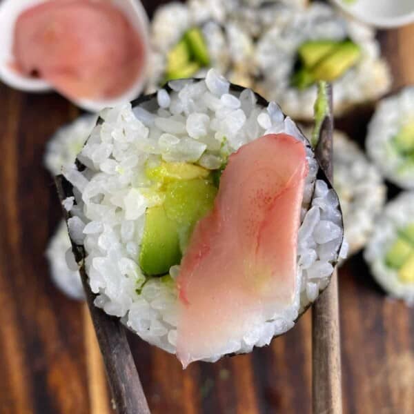 Chopsticks holding an avocado roll