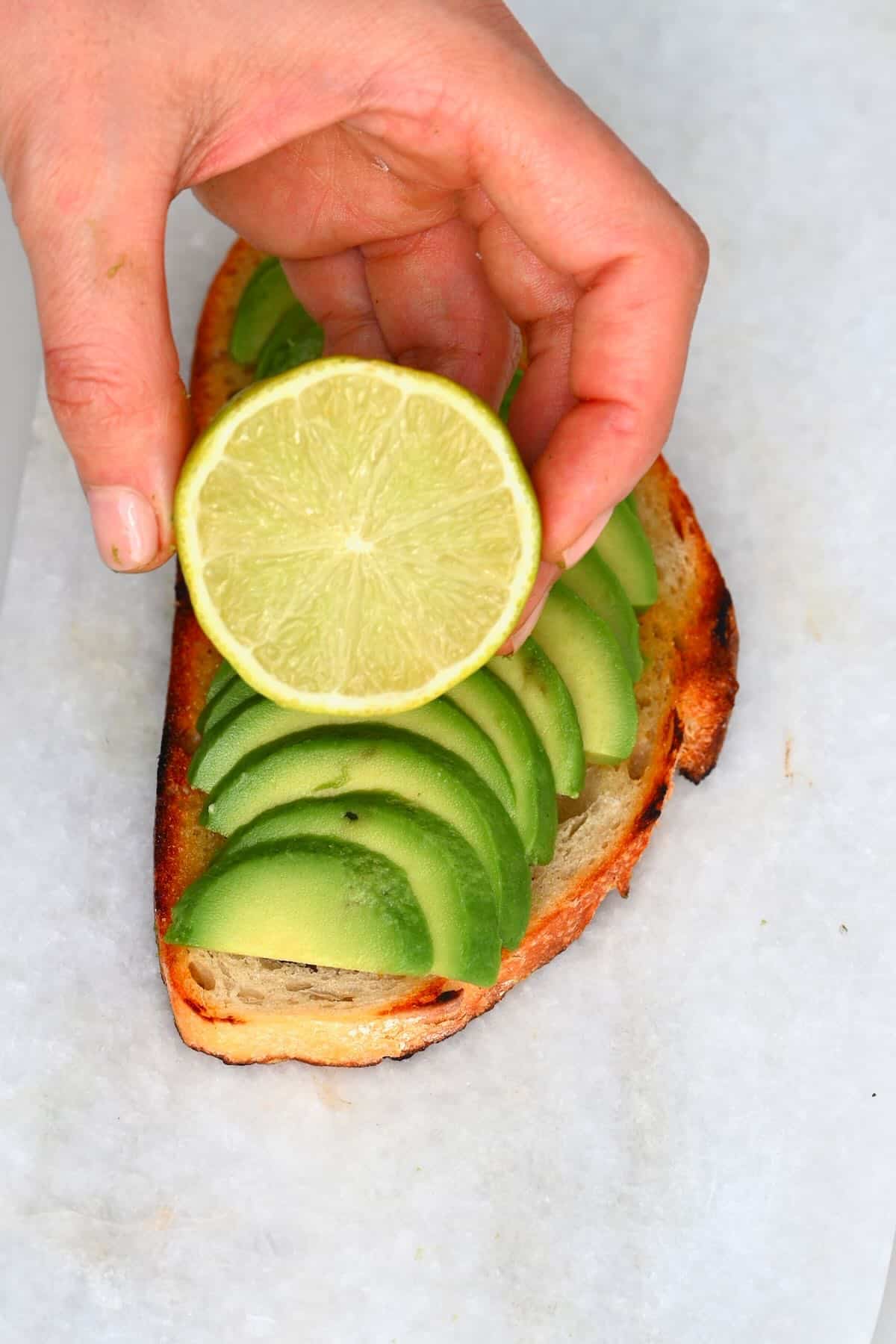 Drizzling lime juice over an avocado toast
