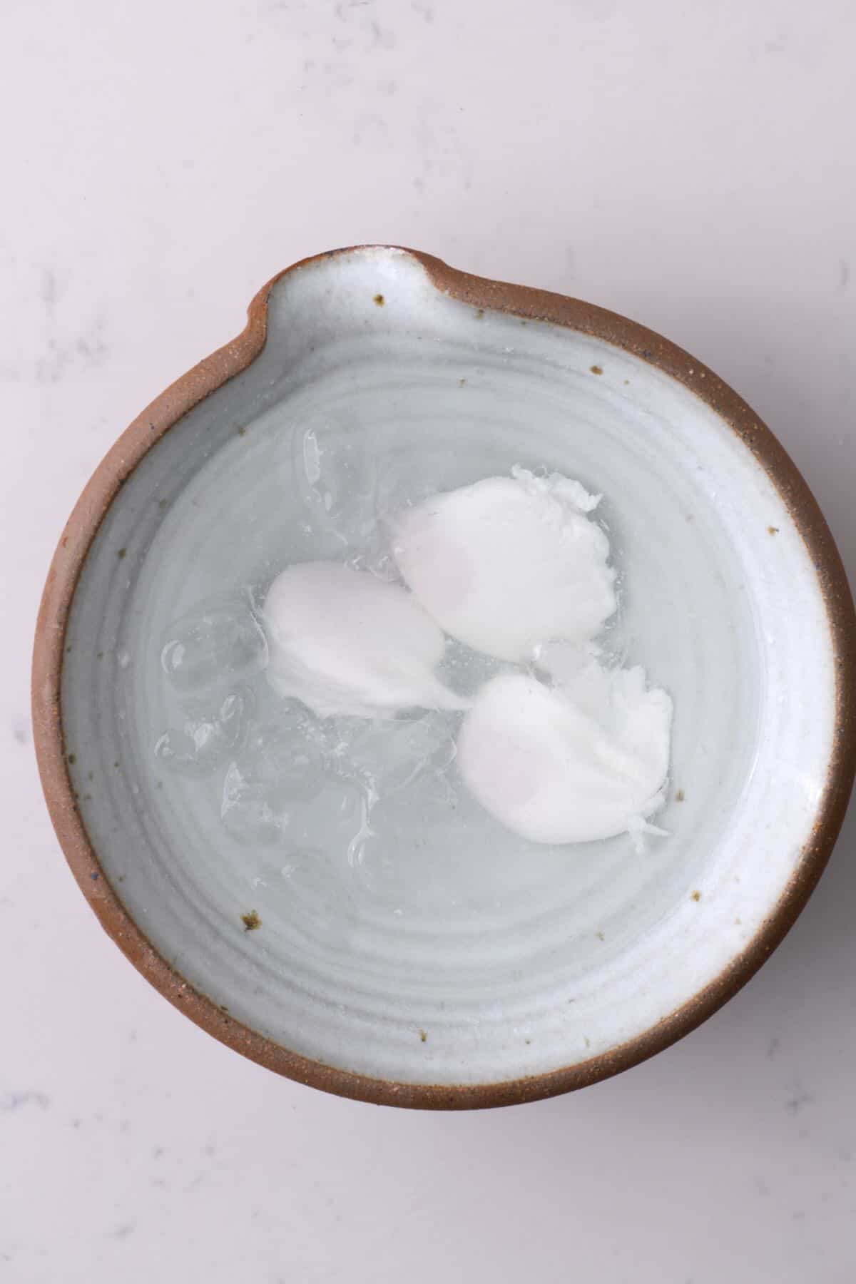 Three poached eggs in an ice bath