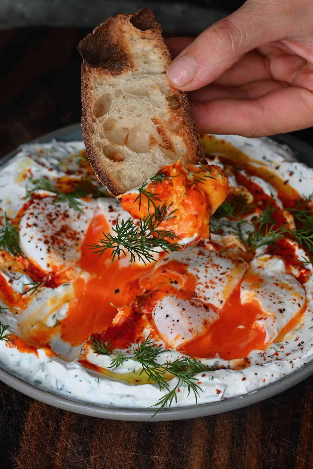Bread dipped in Turkish eggs topped with dill