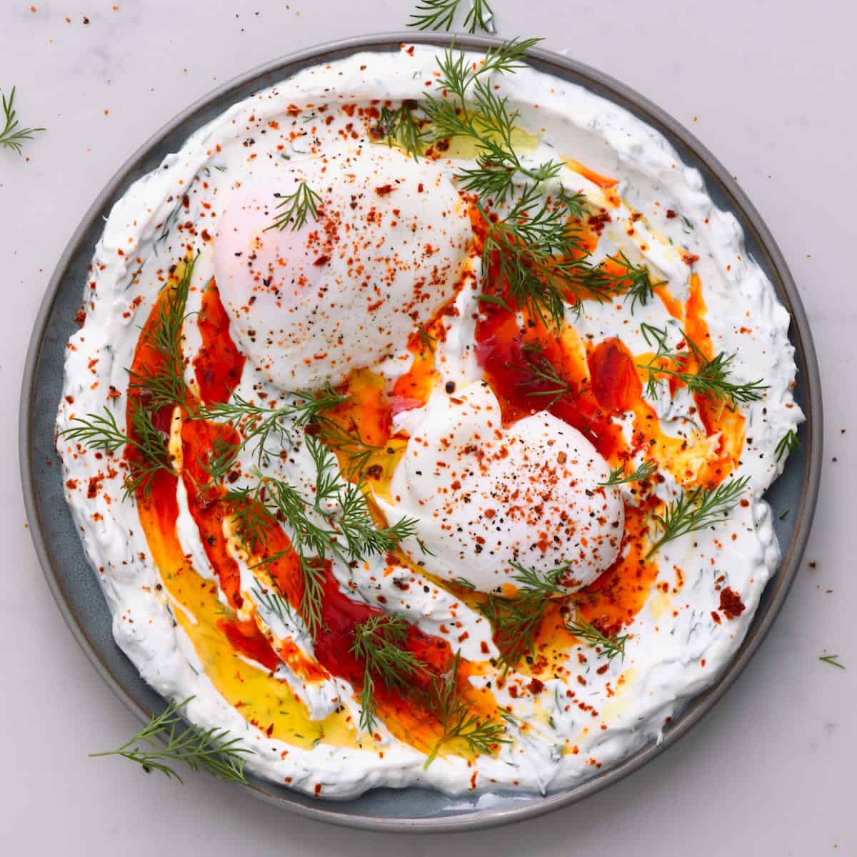 Turkish eggs topped with dill in a plate