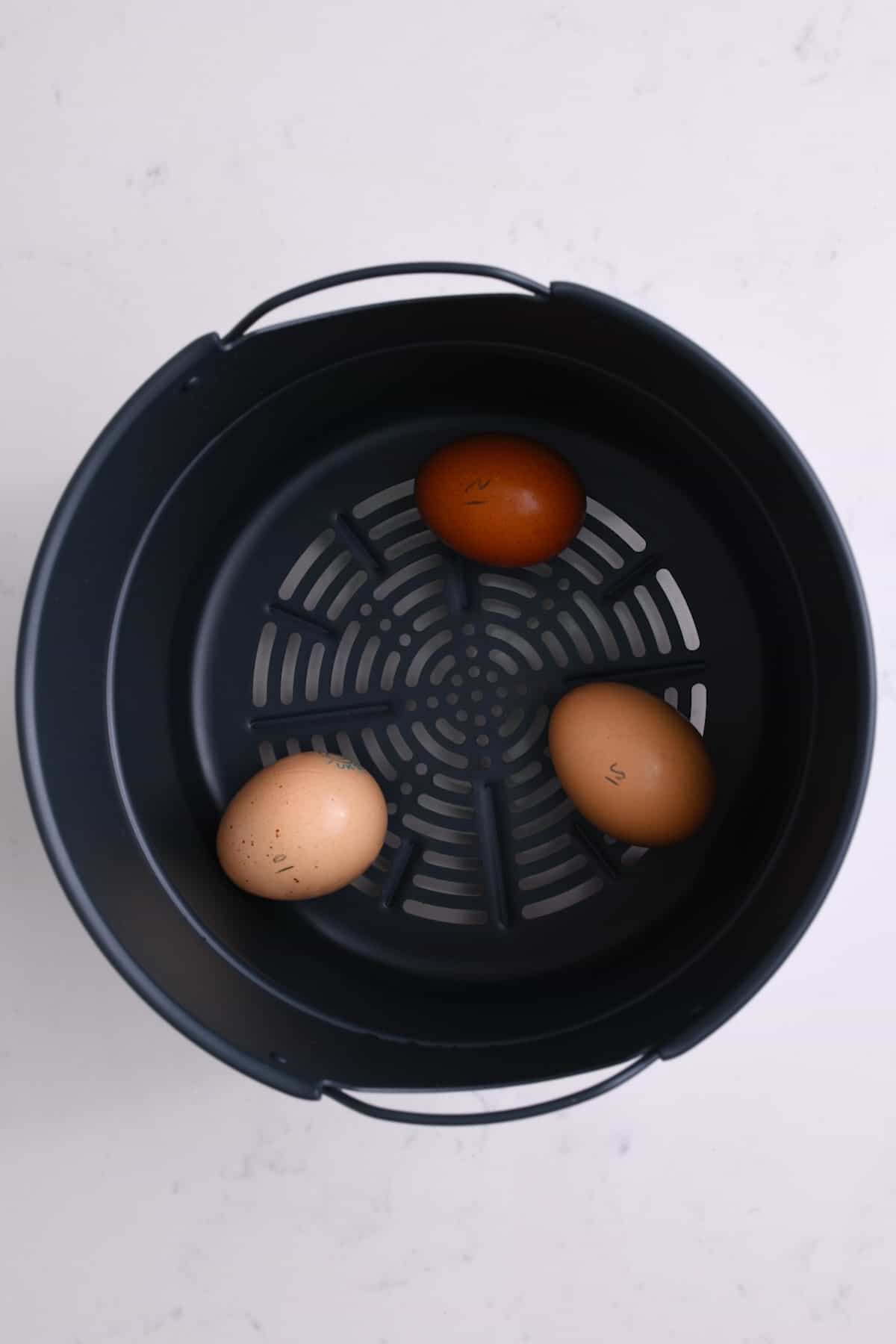 Three eggs in an air fryer basket