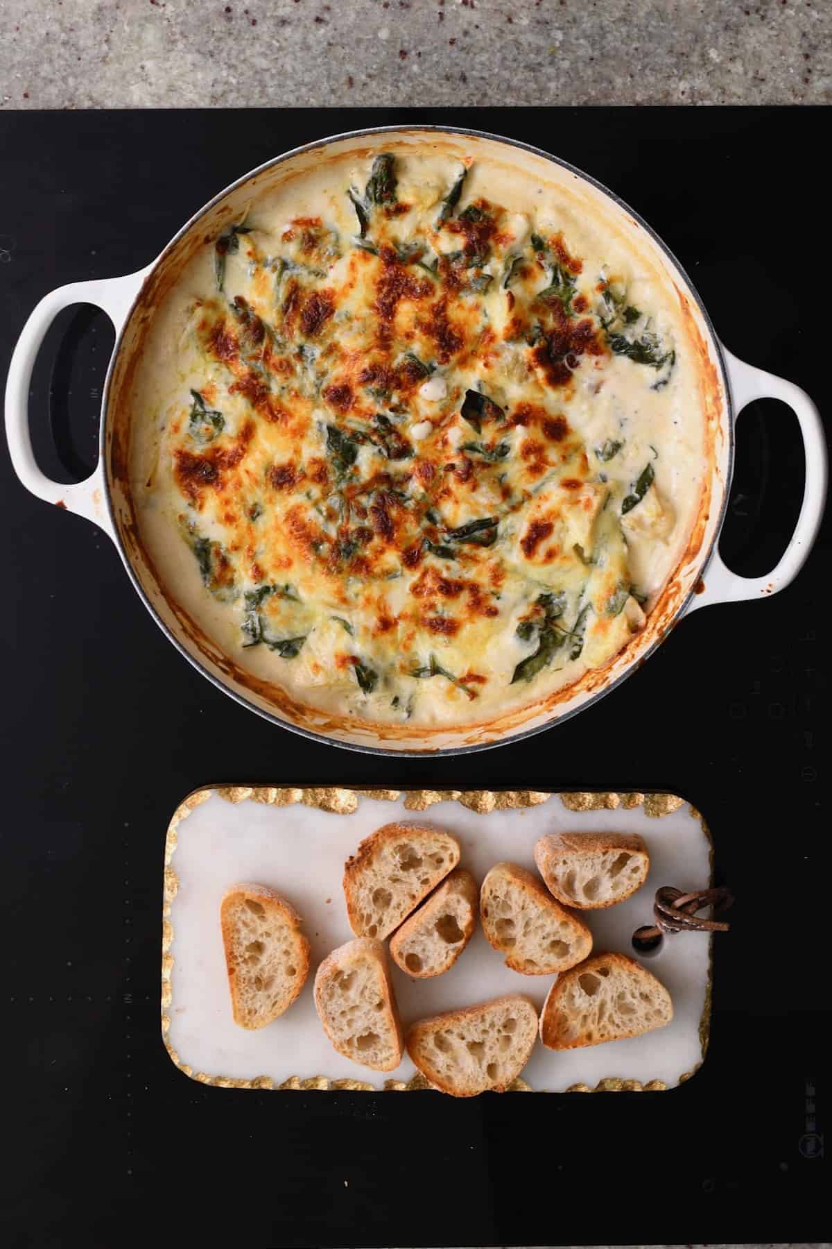 Artichoke Spinach Dip in a pan and toasted bread next to it