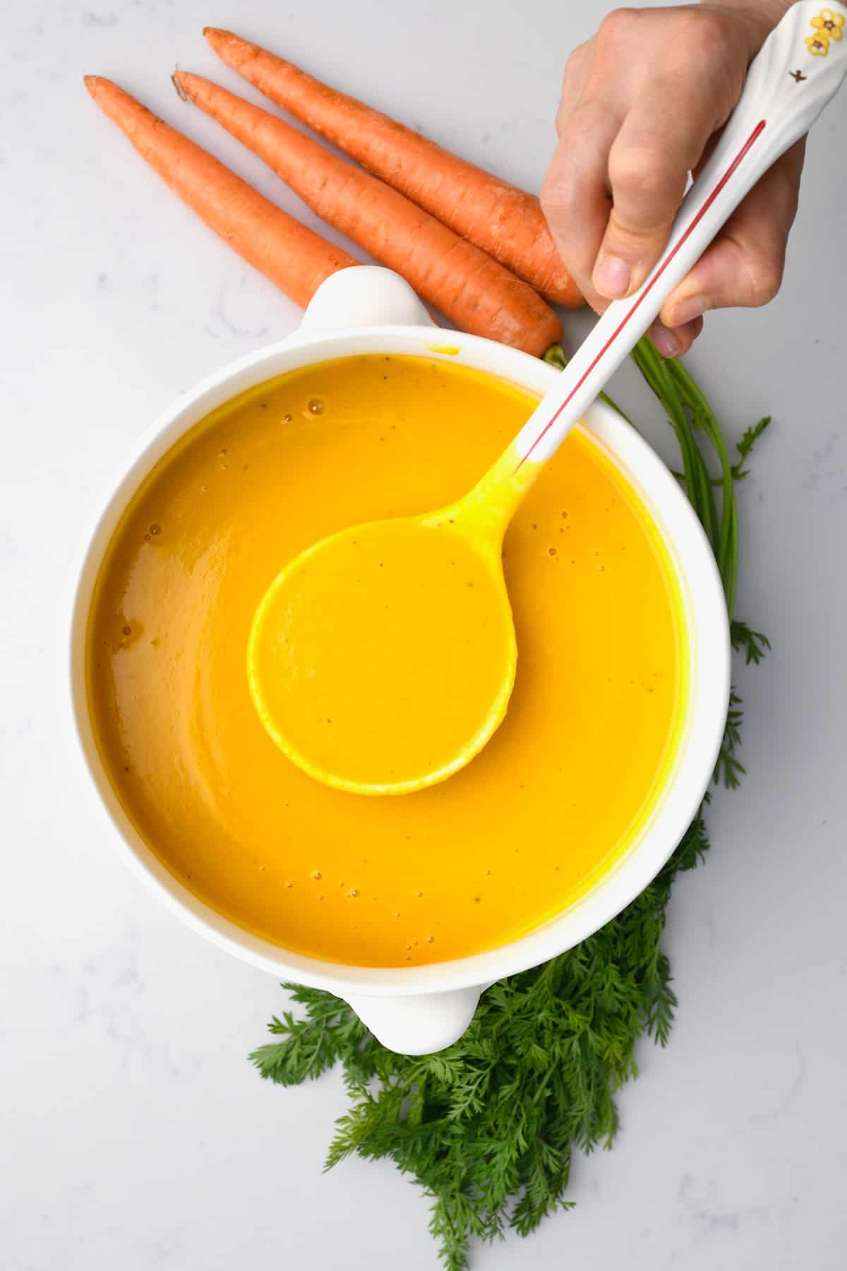 A pot and a ladle with carrot ginger soup