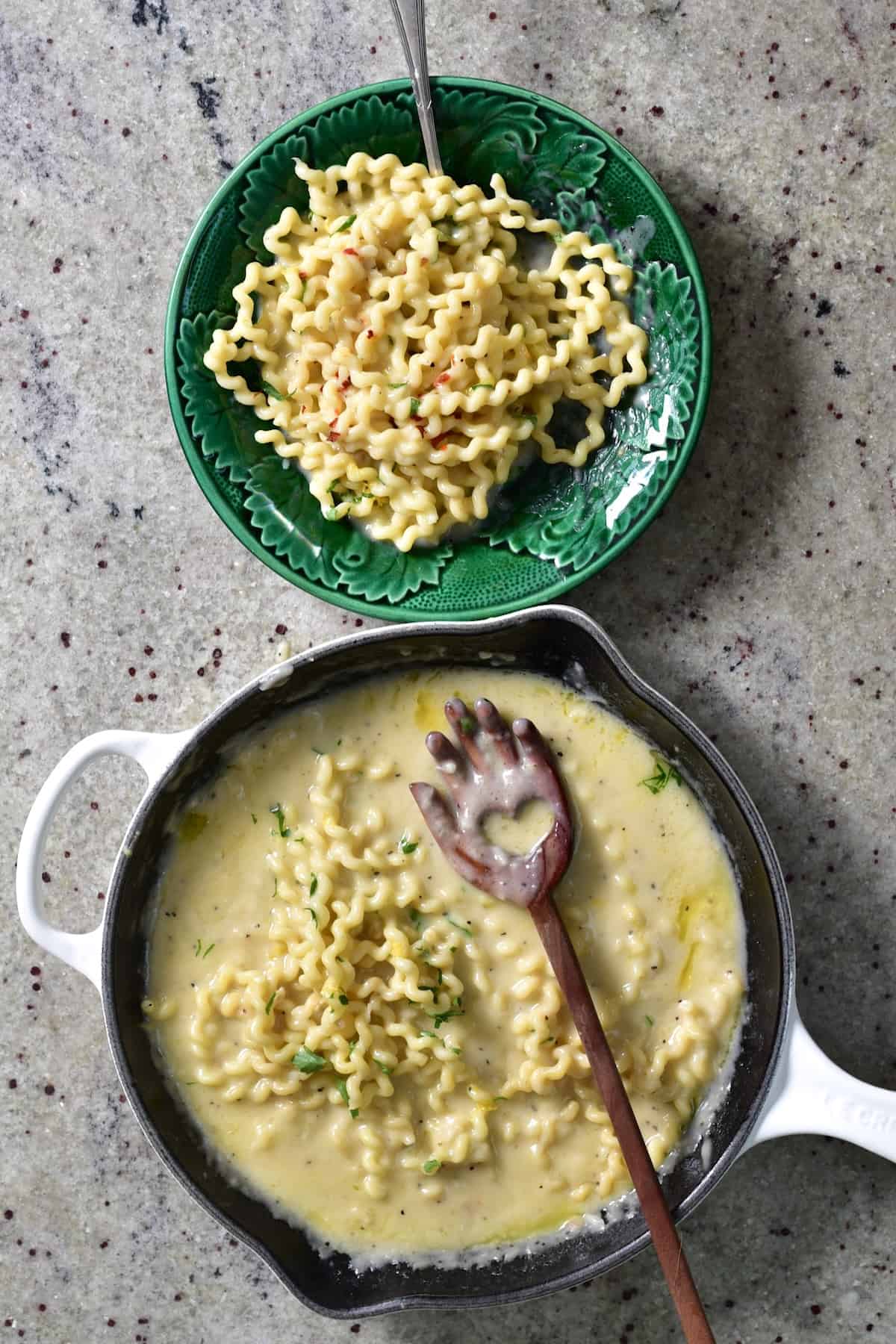 A saucepan and a bowl with garlic cream sauce pasta