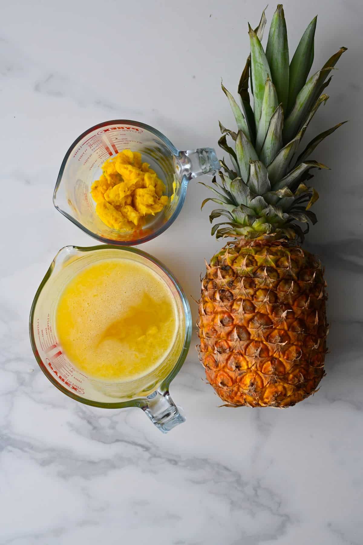 A jug with fresh juice from pineapple and a pineapple next to it