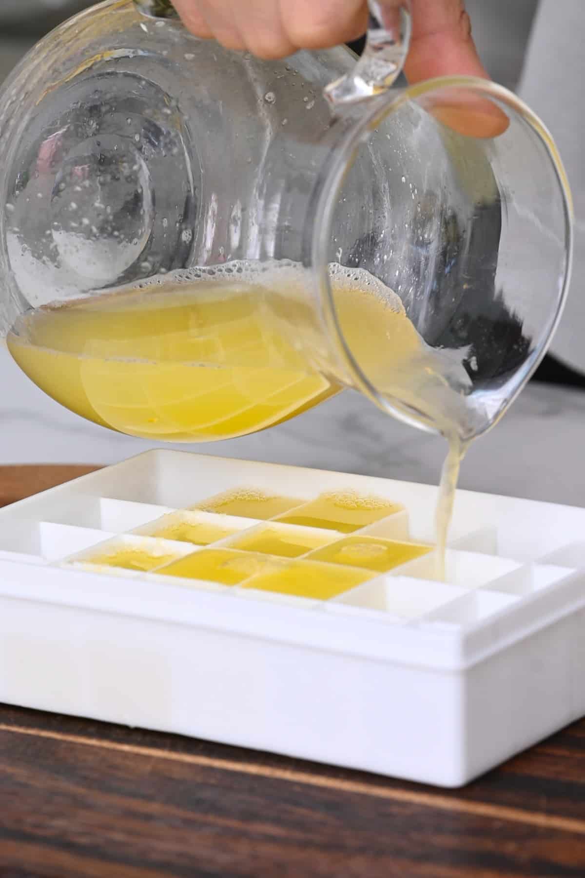 Pouring lemon juice in an ice cube tray