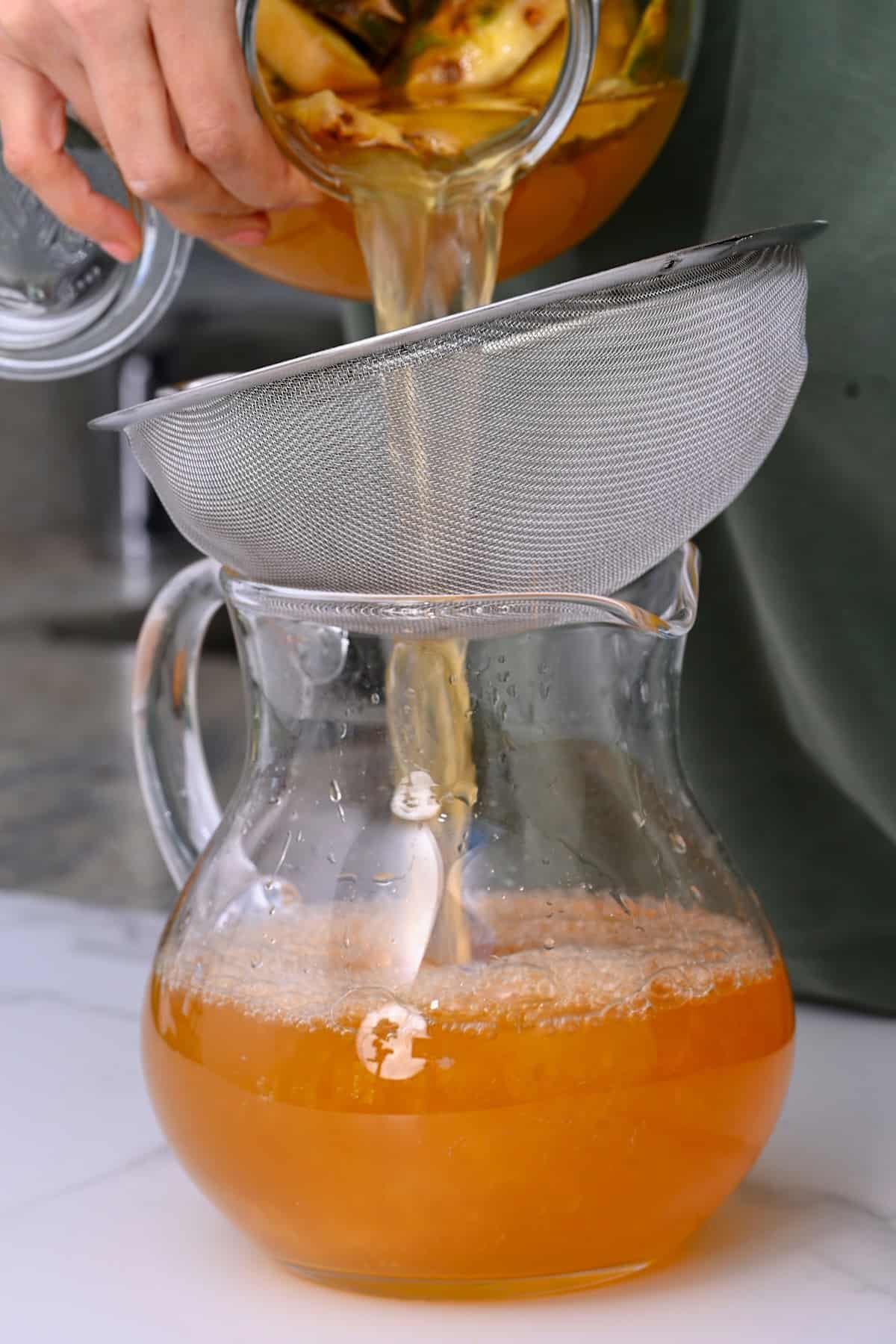 Sieving tepache in a jug