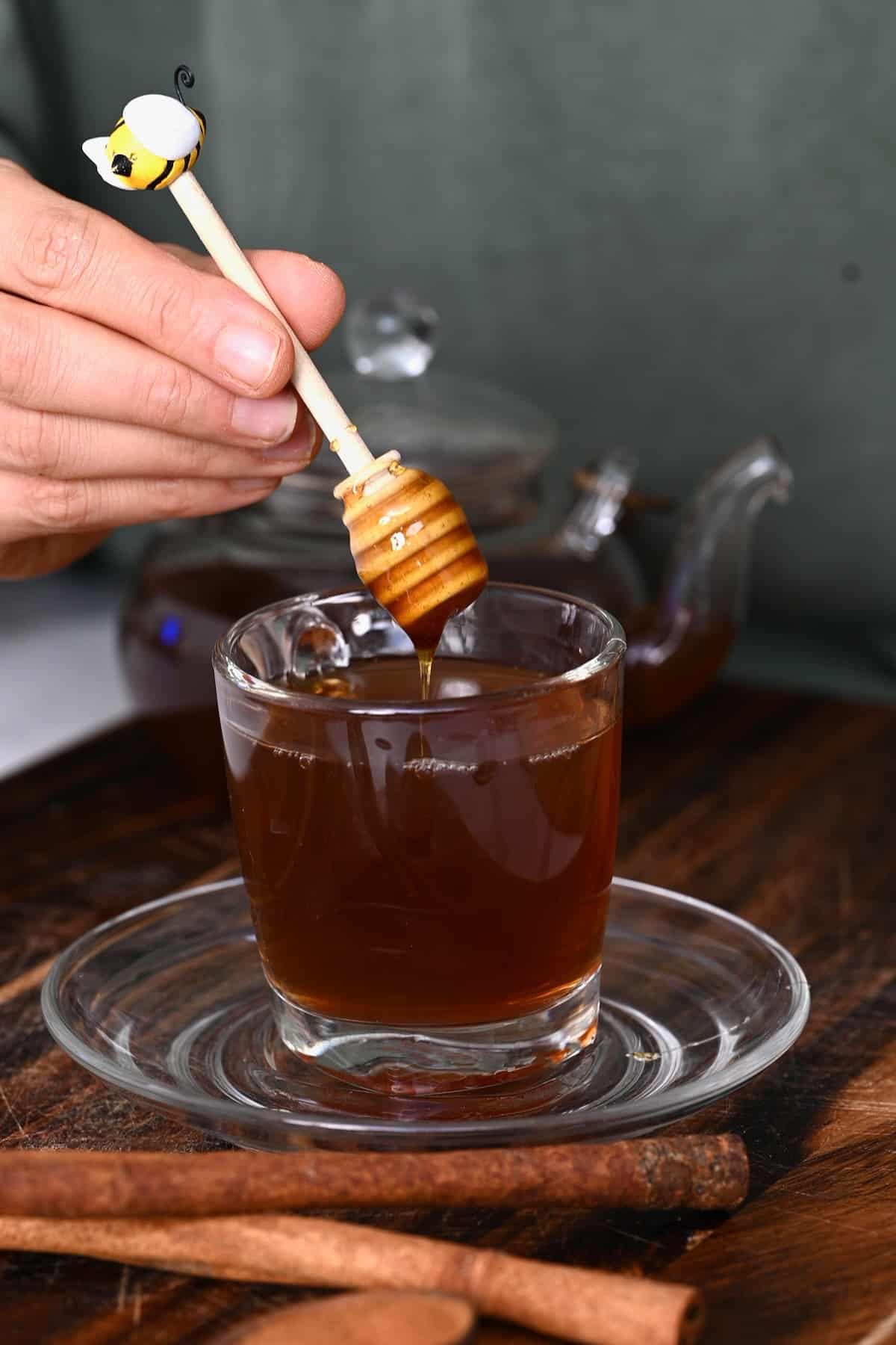 Adding a bit of honey to a glass with tea
