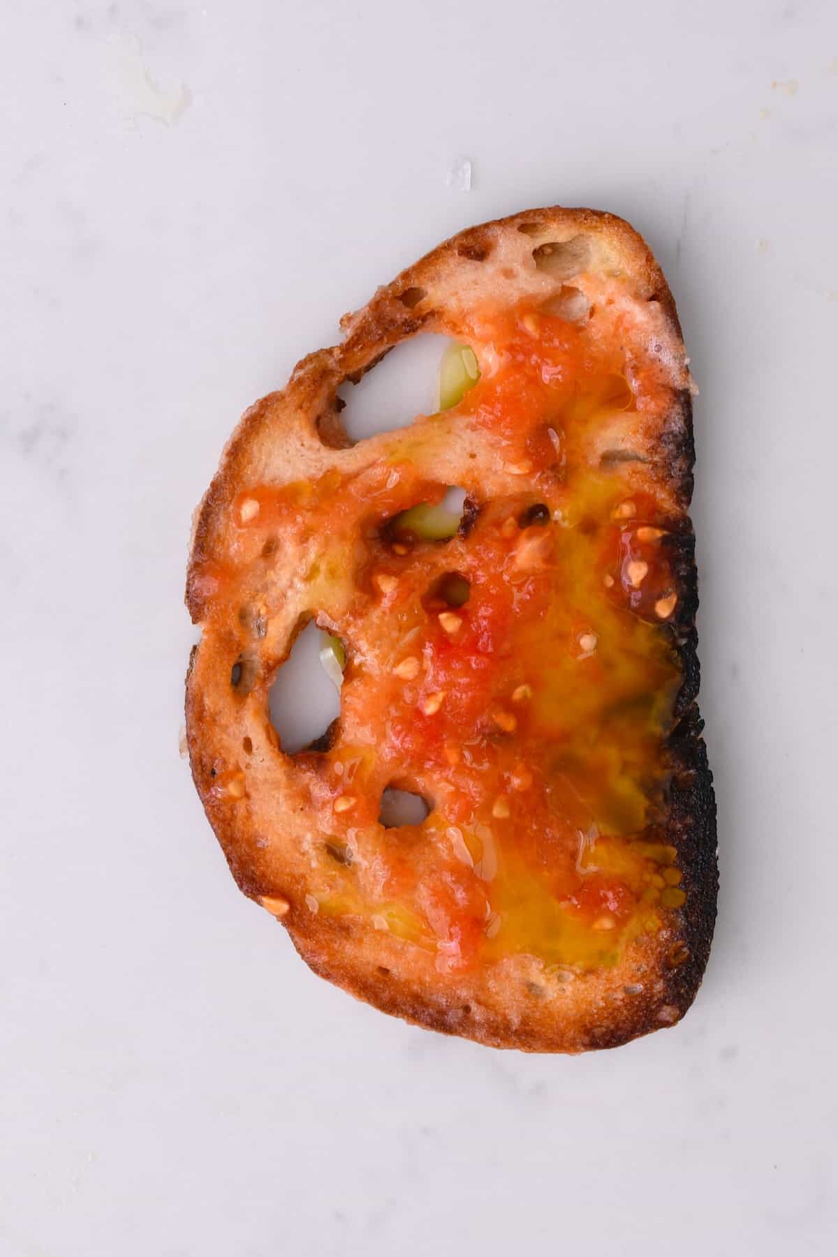 A slice of bread topped with tomato and olive oil