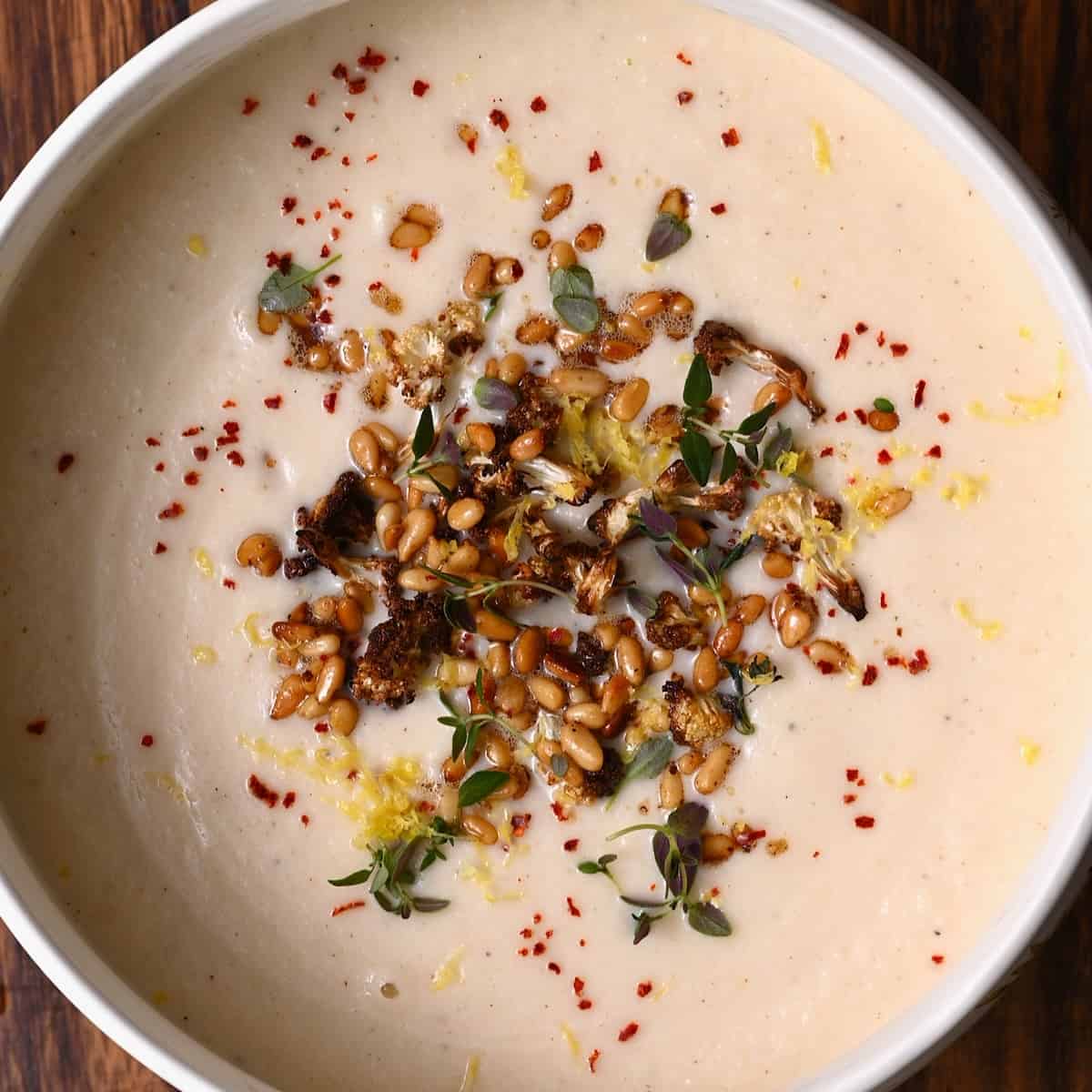Cauliflower soup topped with pine nuts and lemon zest