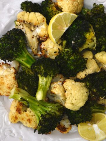 A plate with roasted cauliflower and broccoli with lemon slices