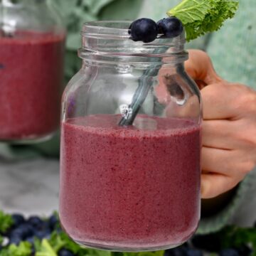 A mason jar with blueberry and kale smoothie