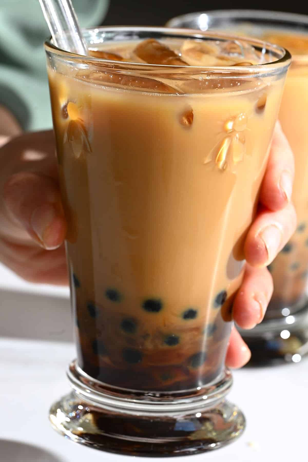 A hand holding a glass with bubble milk tea