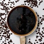 Homemade coffee syrup in a pot with coffee beans around it - 13