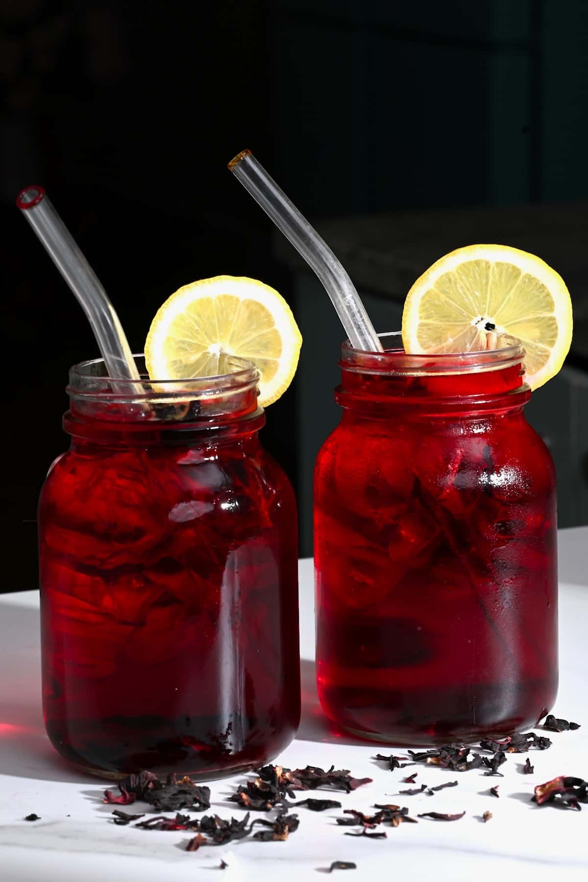 Hibiscus tea in two mason jars topped with lemon slices