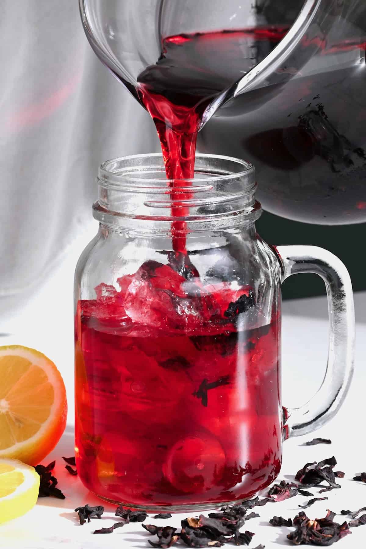 Pouring iced hibiscus tea in a mason jar