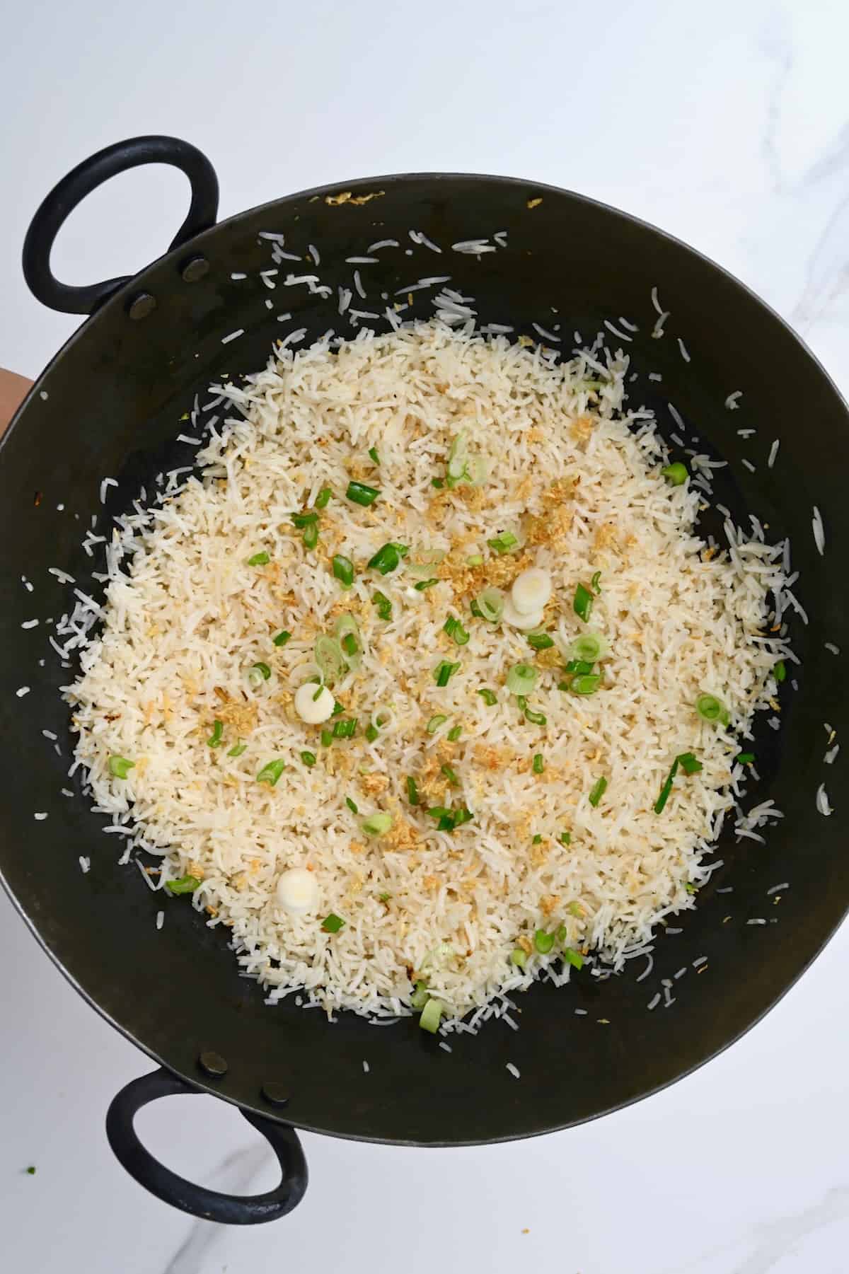 Garlic rice topped with green onion in a pan