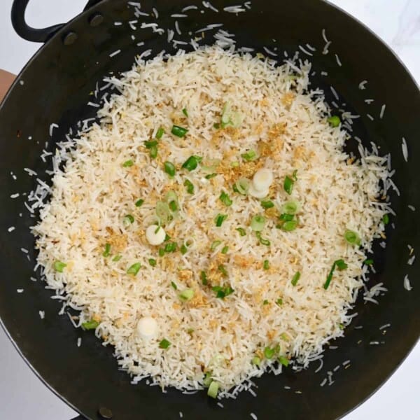 Garlic rice topped with green onion in a pan