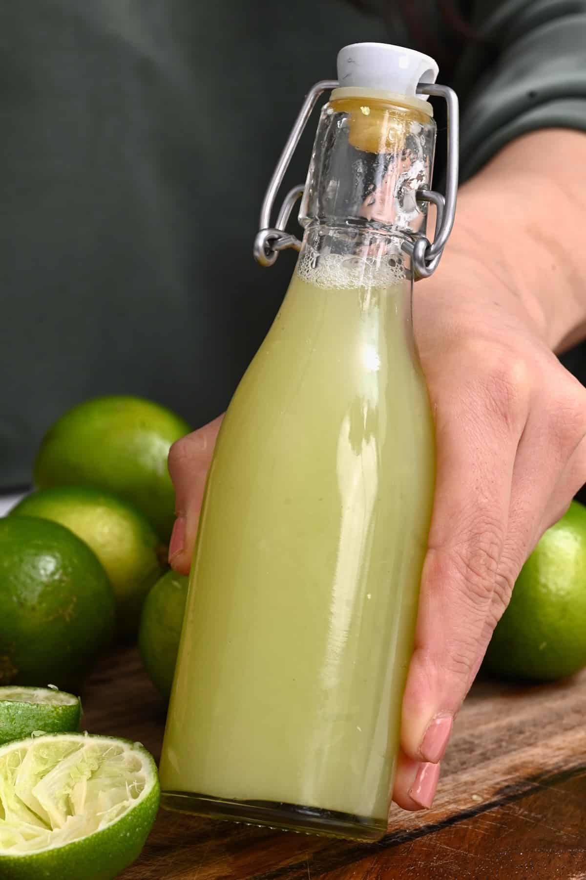 Hand holding a small bottle with lime juice