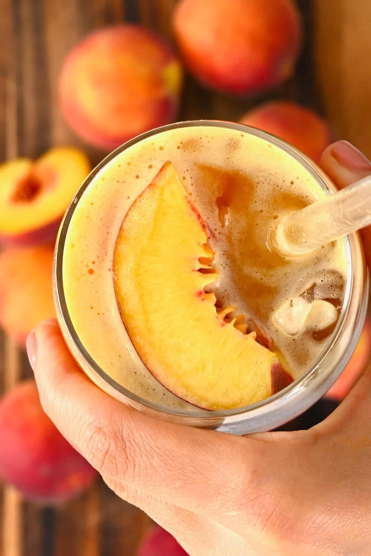 Top view of a glass with peach juice topped with a peach slice