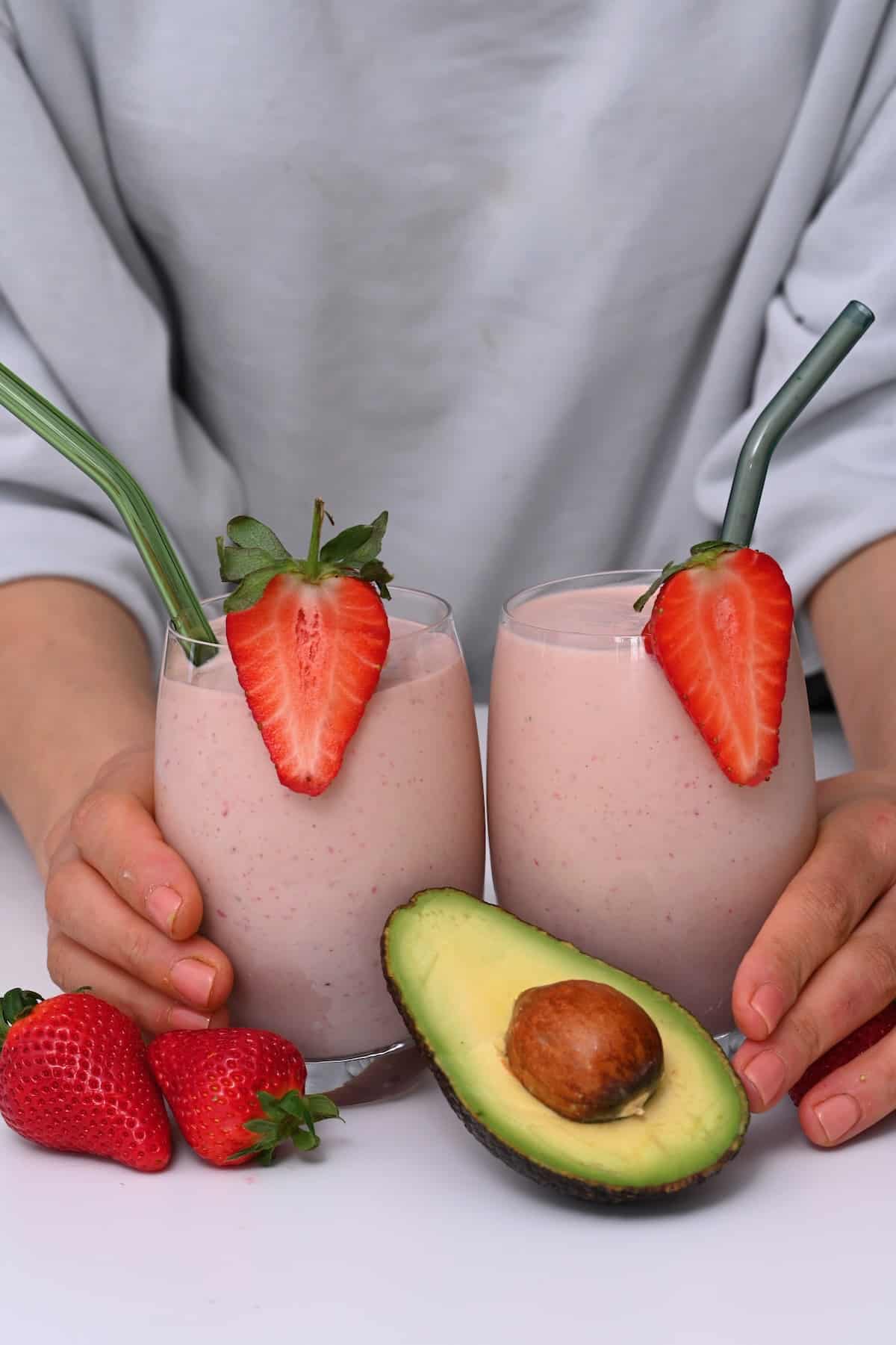 Two glasses with pink smoothie topped with strawberries
