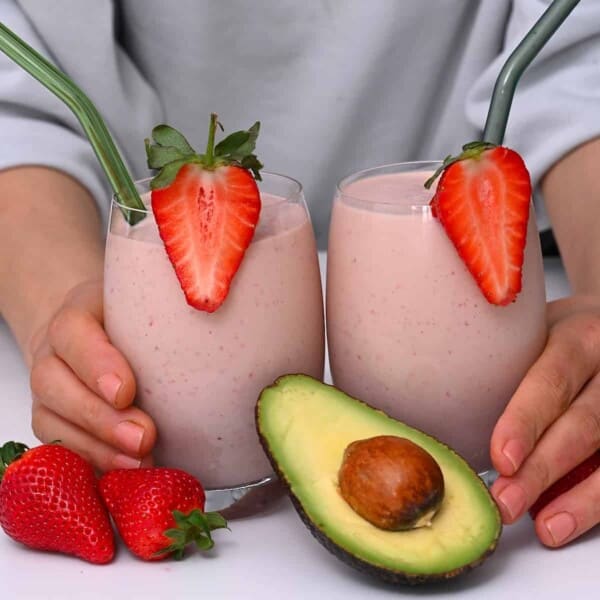 Two glasses with pink smoothie topped with strawberries