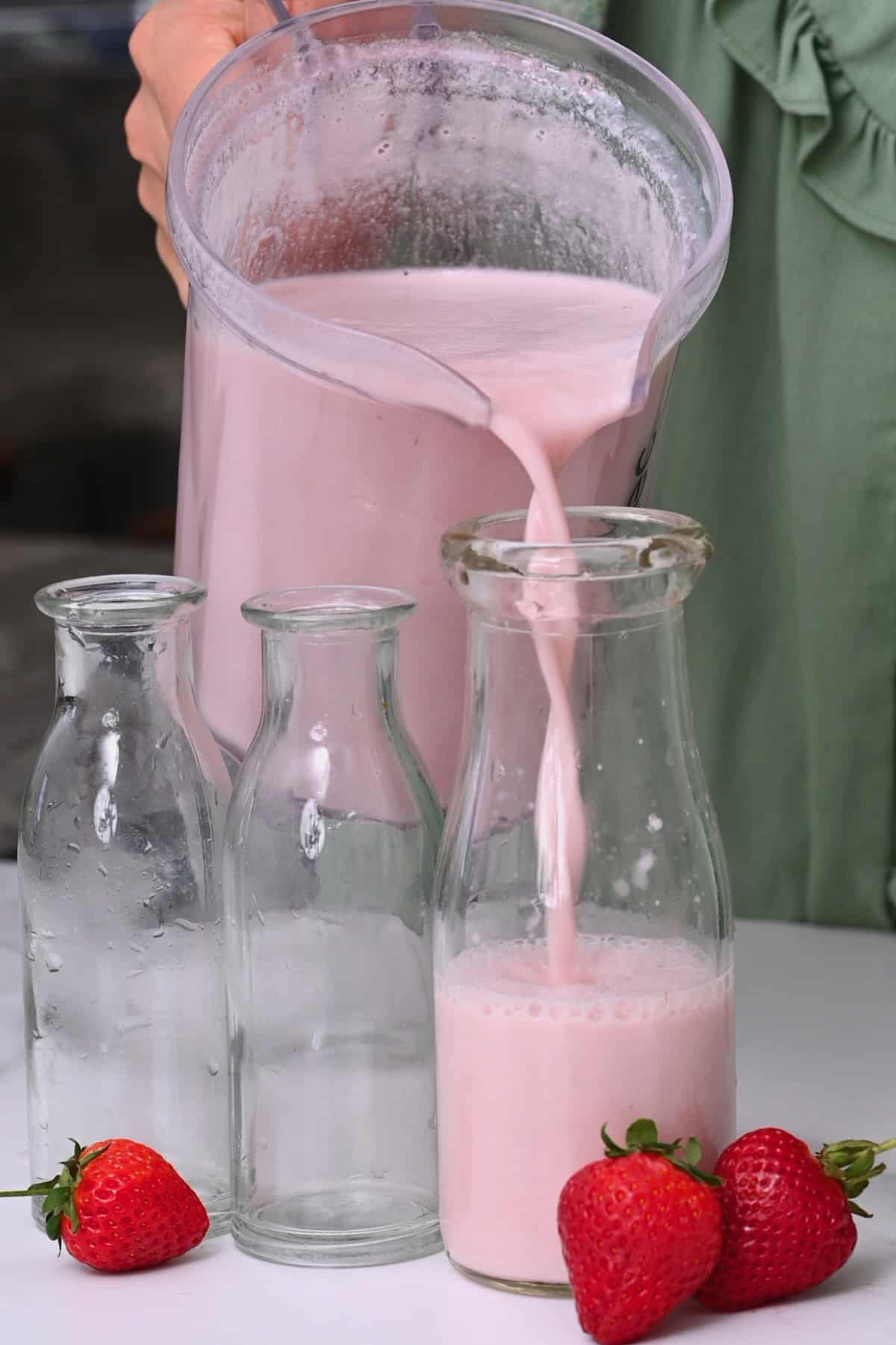 Pouring strawberry milk from a blender to a bottle