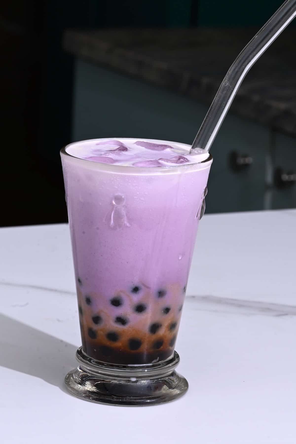 A glass with a straw and taro milk bubble tea