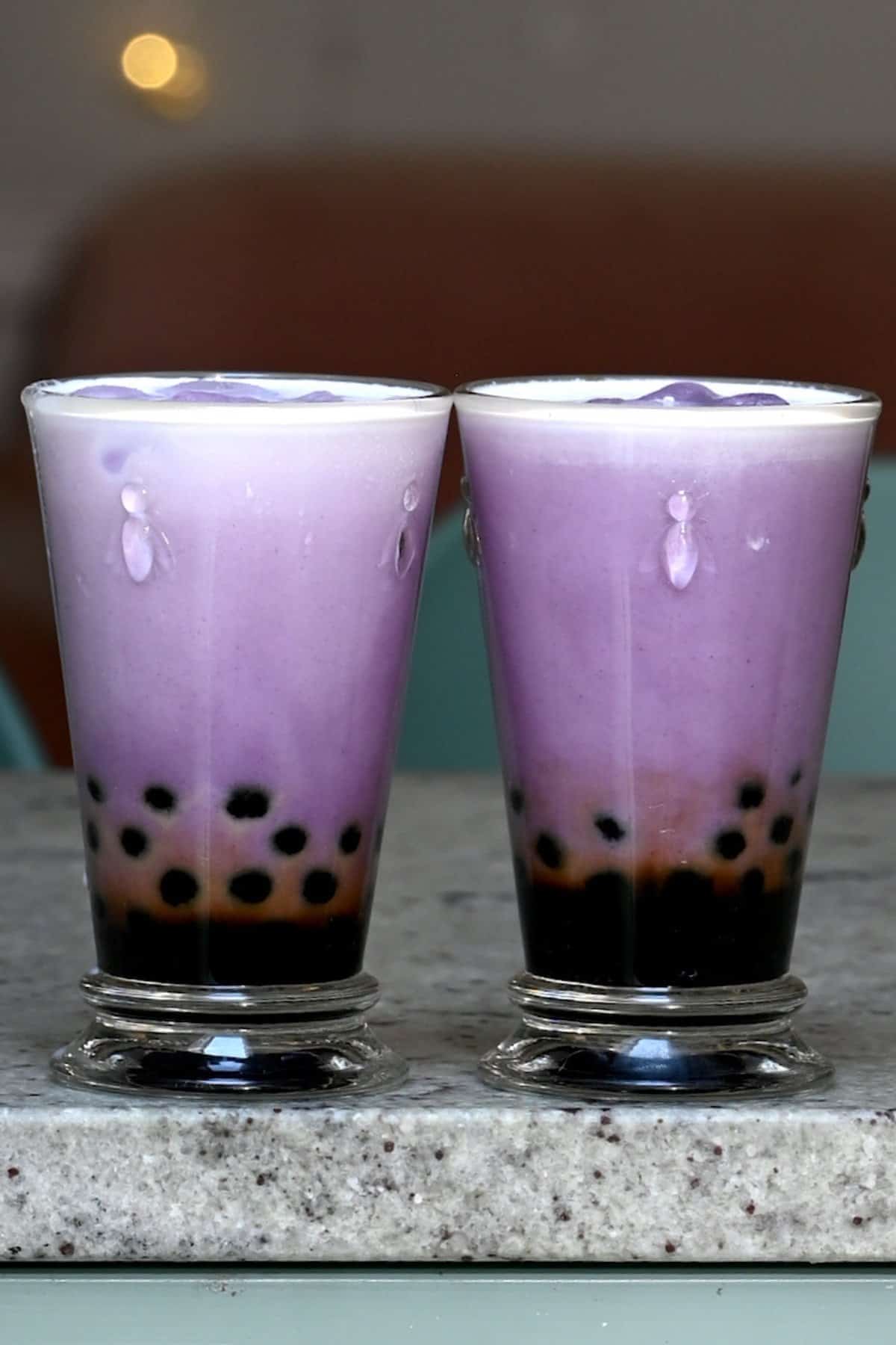 Two glasses with boba and taro milk tea