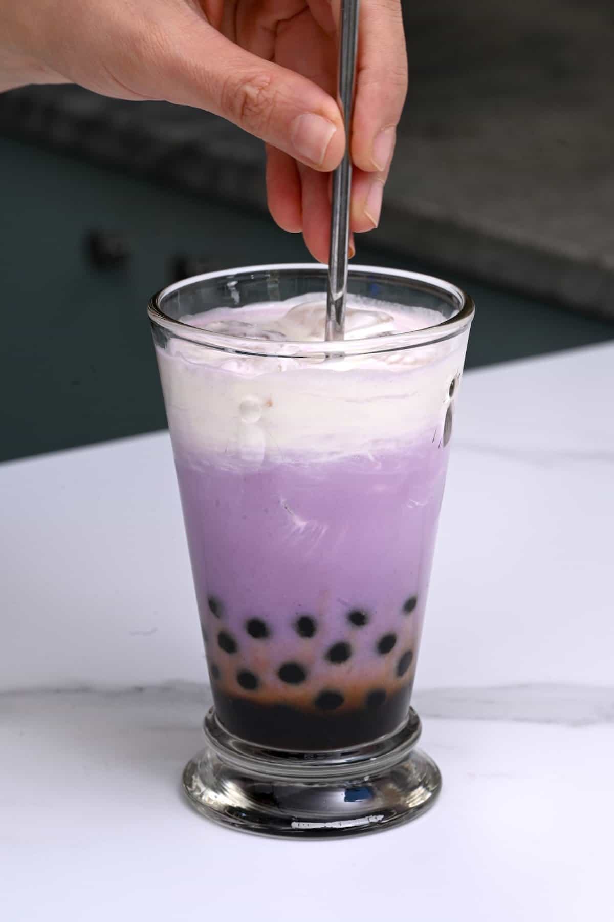 Stirring taro milk tea in a glass