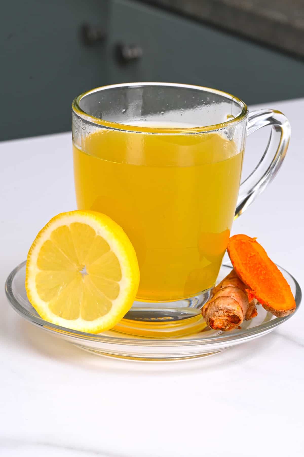 A cup with turmeric tea and lemon slice on the side