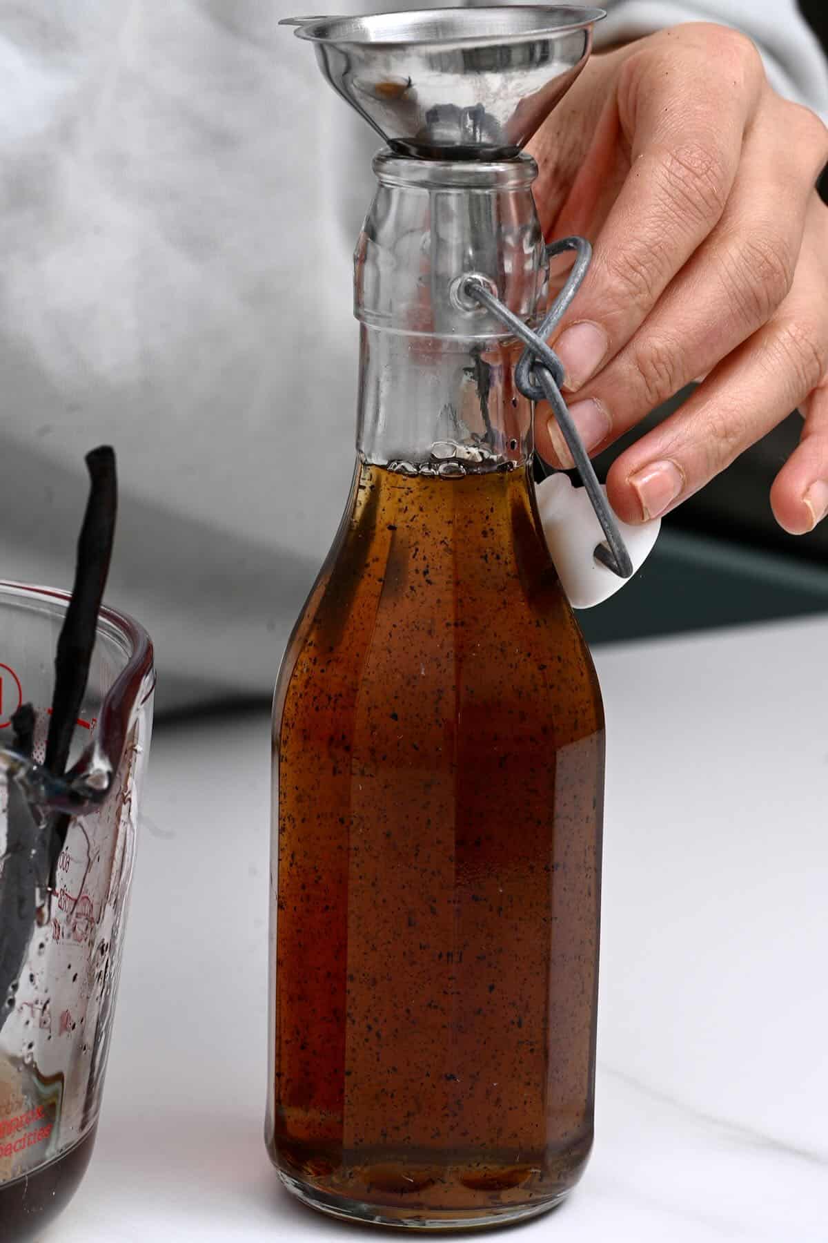 Pouring sugar syrup with vanilla in a bottle