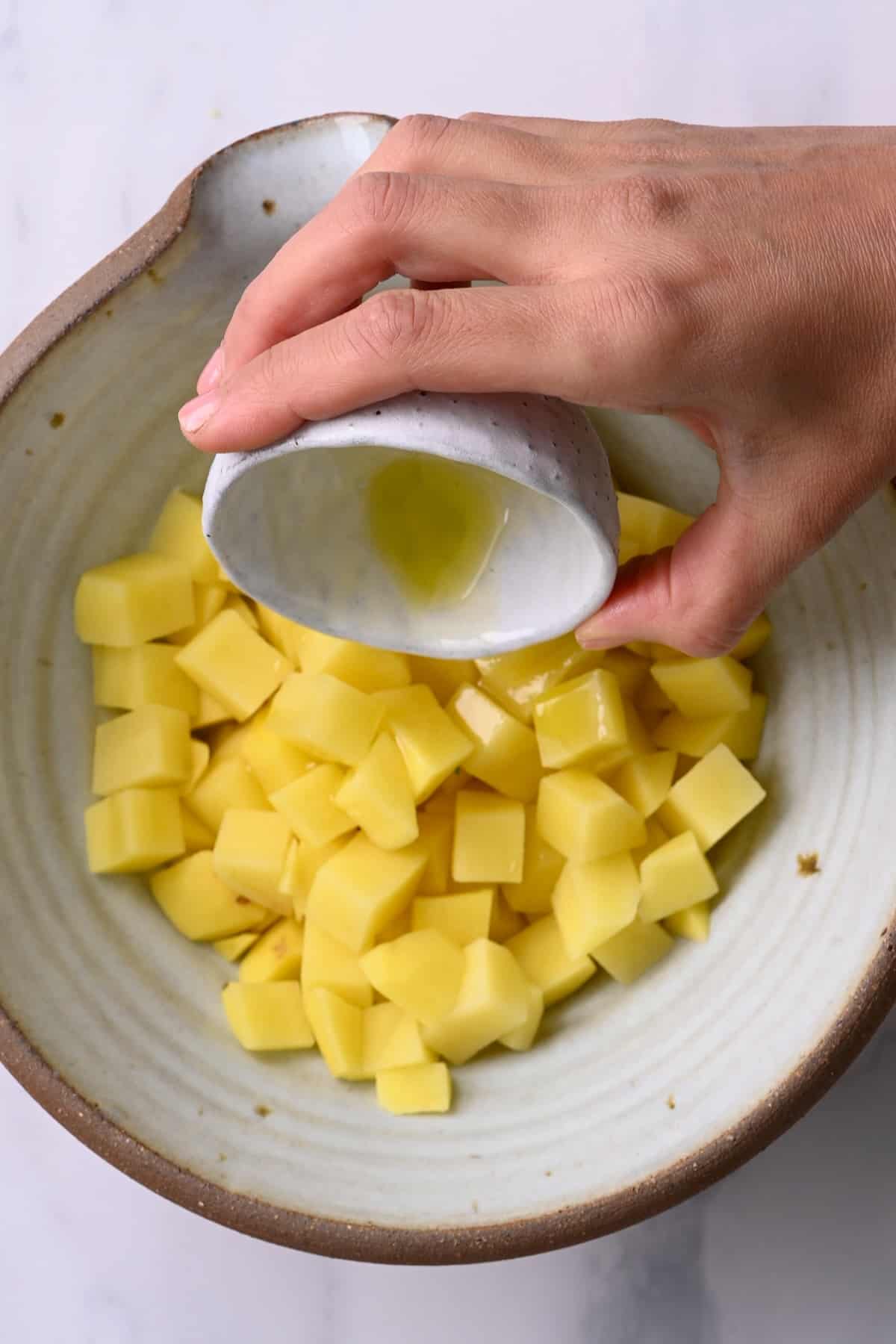 Adding oil to chopped potatoes