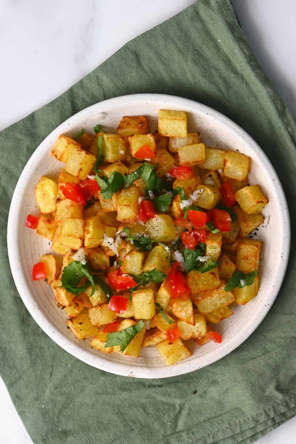 A serving of air fryer potatoes topped with chopped tomatoes and parsley