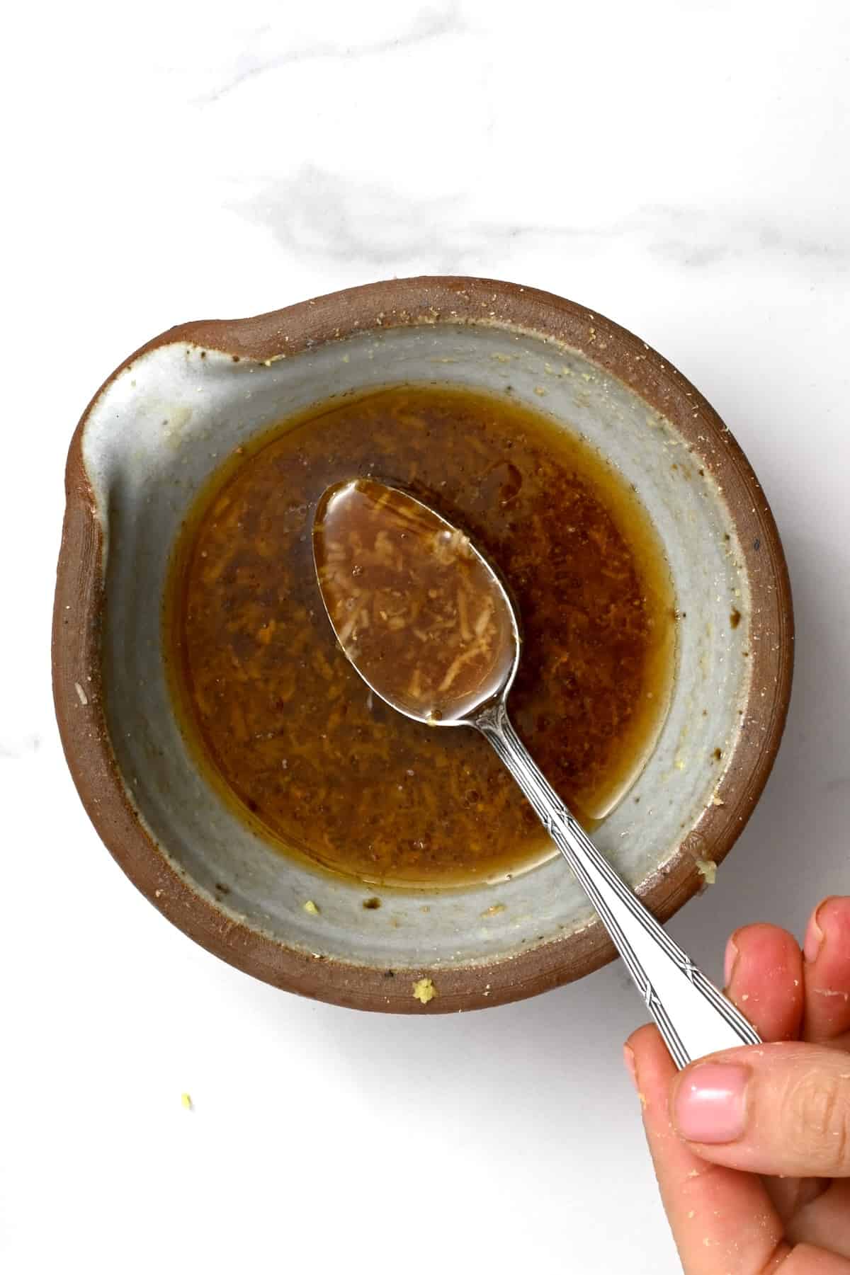 A spoonful of asian salad dressing over a bowl