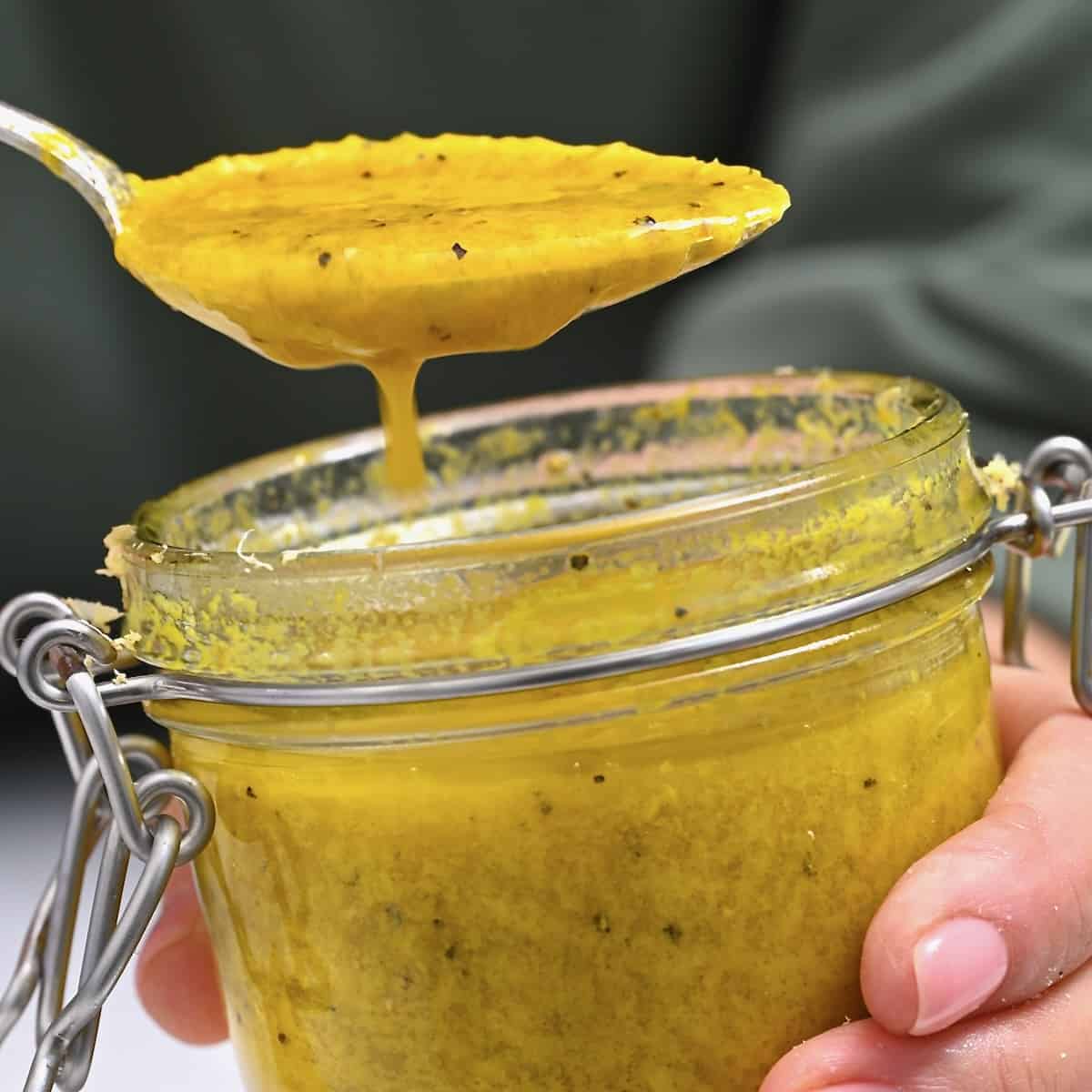 Homemade ginger salad dressing dripping from a spoon over a jar